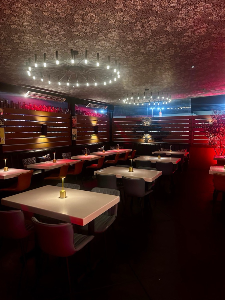 Bei's main dining room at night, white tables under a ring chandelier and warm red light